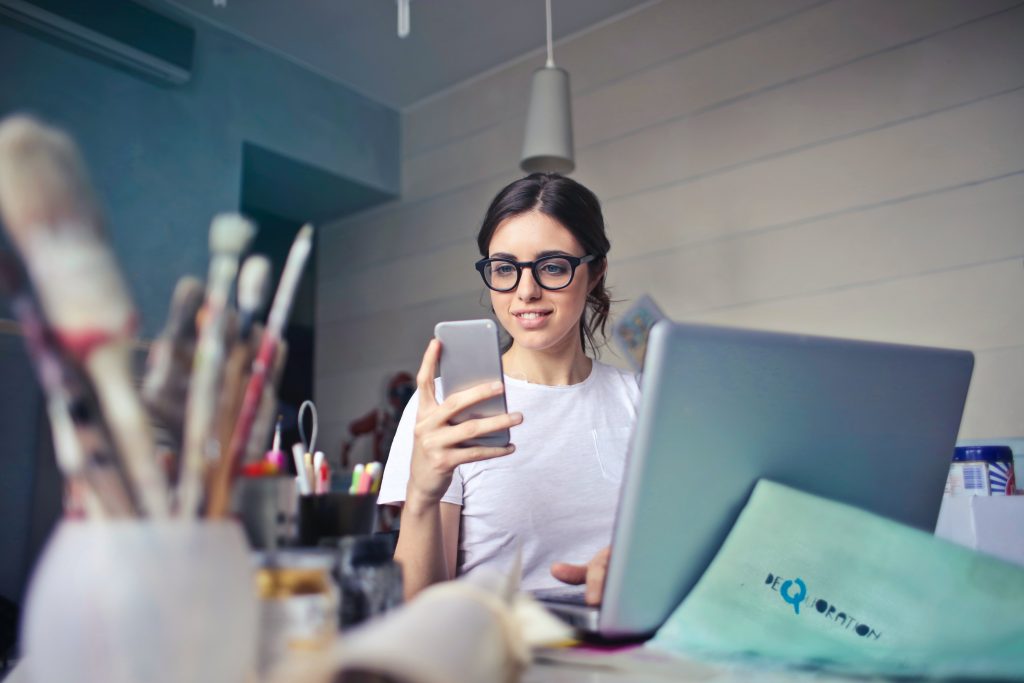 Young creative person at a desk looking at their phone