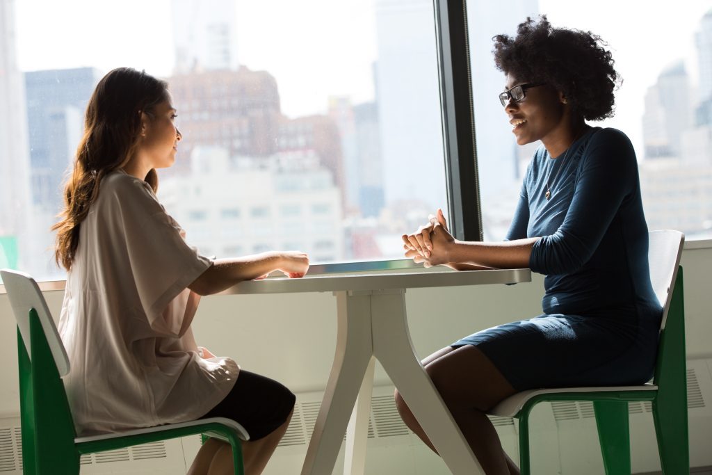 Two people chatting over a small white circular table