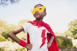 Child dressed as a superhero with a red cape and yellow mask