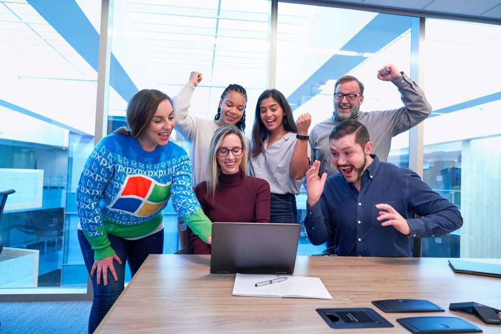 Office workers celebrating around a laptop