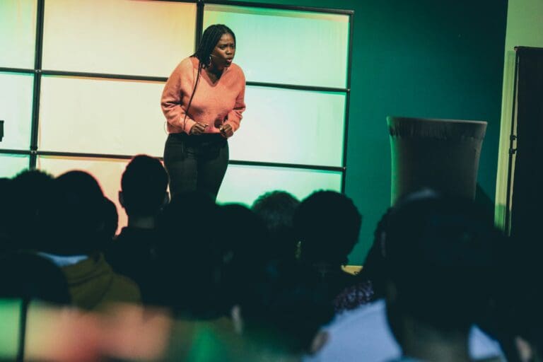 person in an orange top speaking on stage