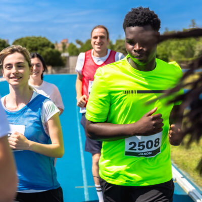 Runners competing fiercely in a race on a vibrant blue track, showcasing their determination and effort in pursuit of victory