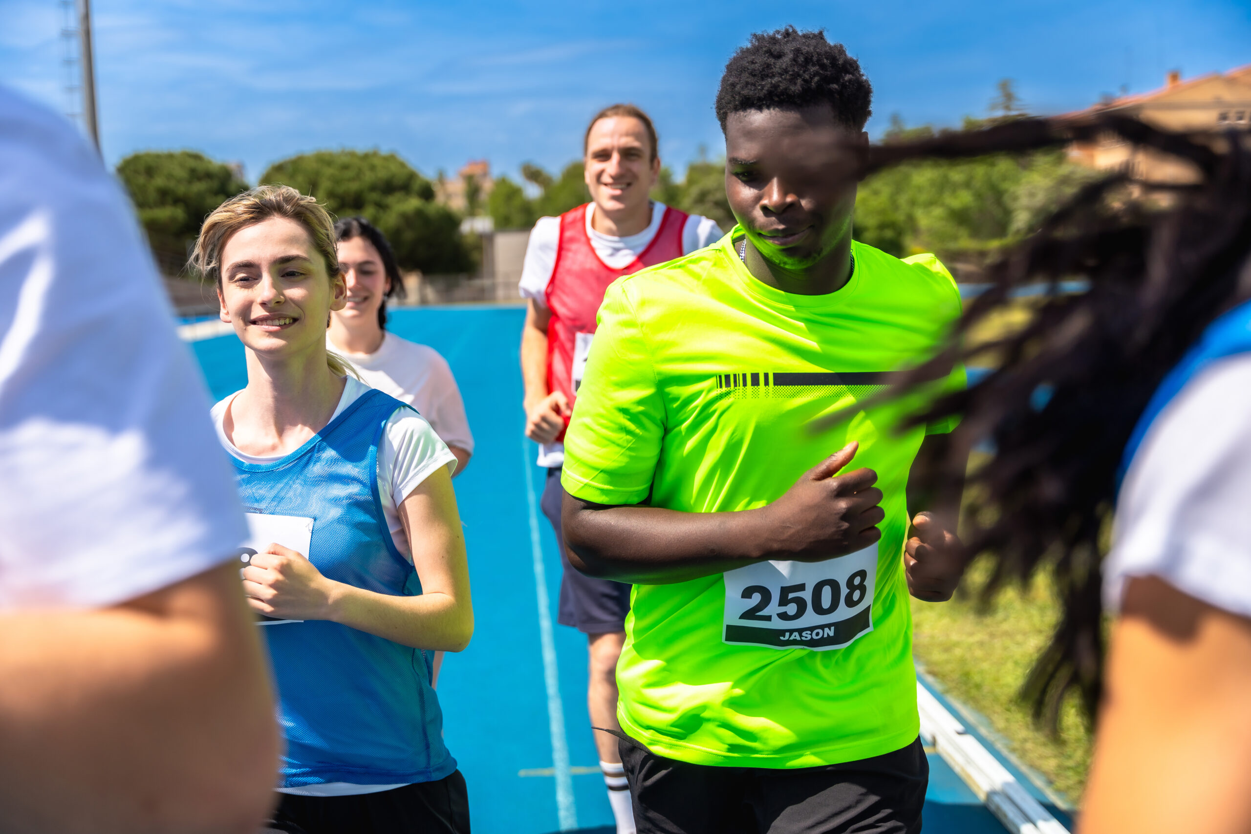 Runners competing fiercely in a race on a vibrant blue track, showcasing their determination and effort in pursuit of victory