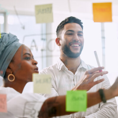 A team looking at sticky notes on a clear window in a boardroom