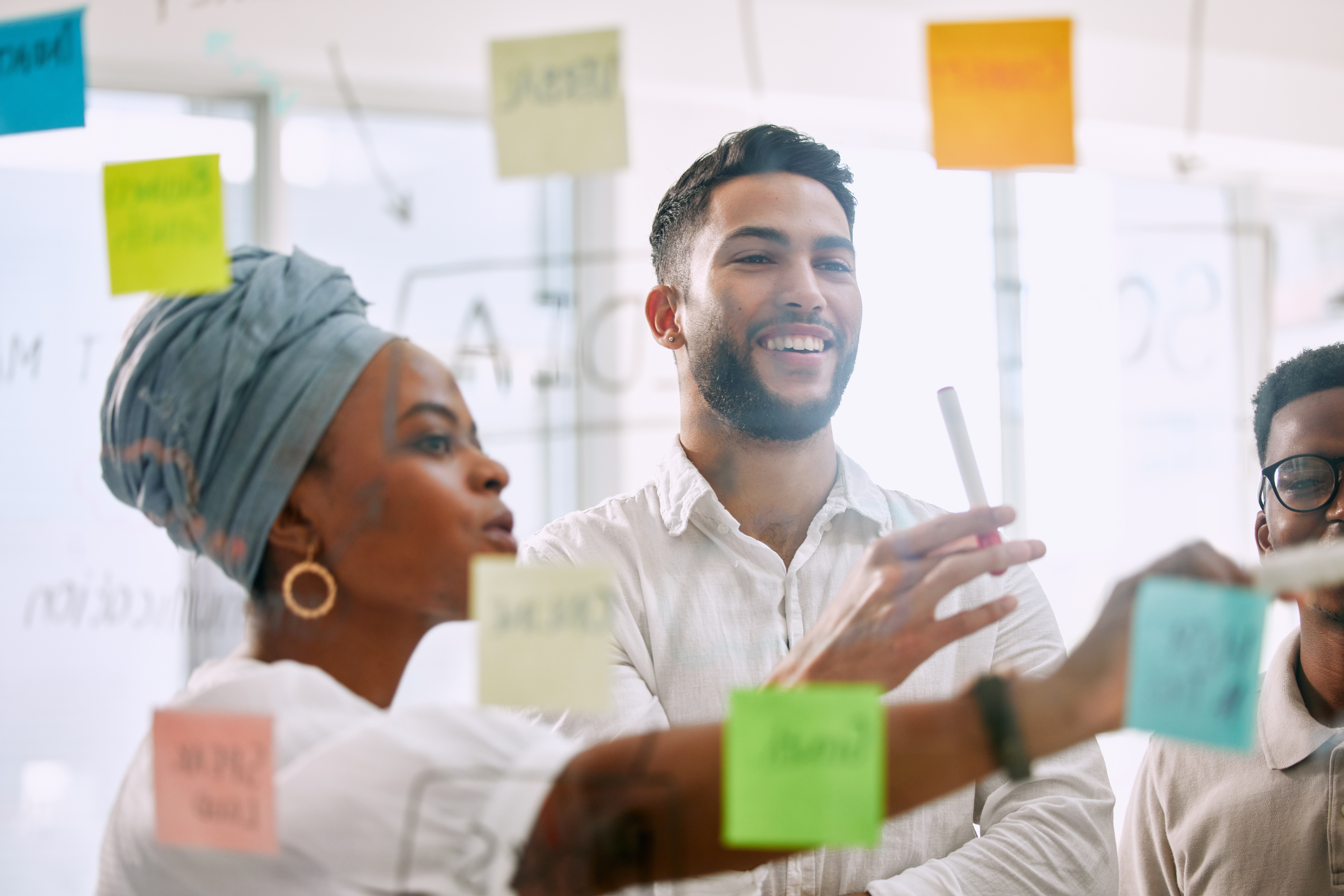 A team looking at sticky notes on a clear window in a boardroom